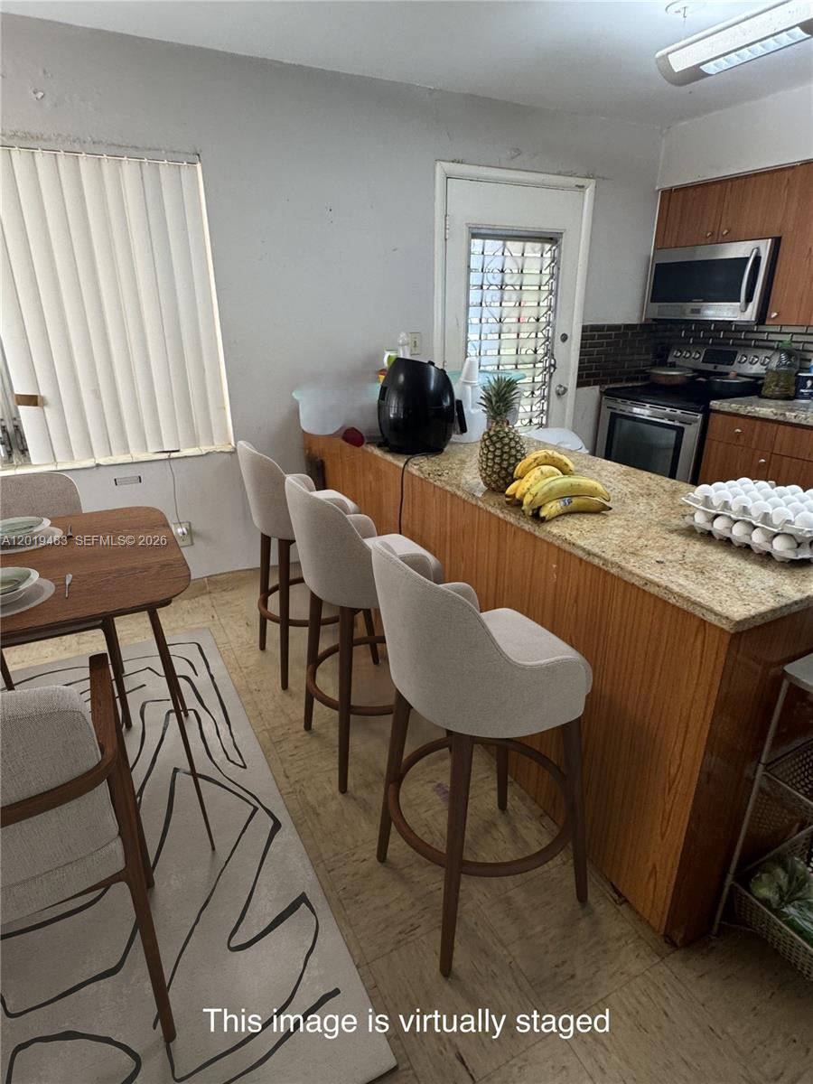 A kitchen features a granite breakfast bar with three stools and a dining area — 224 NE 47th St, Miami FL 33137, MIAMI, FL