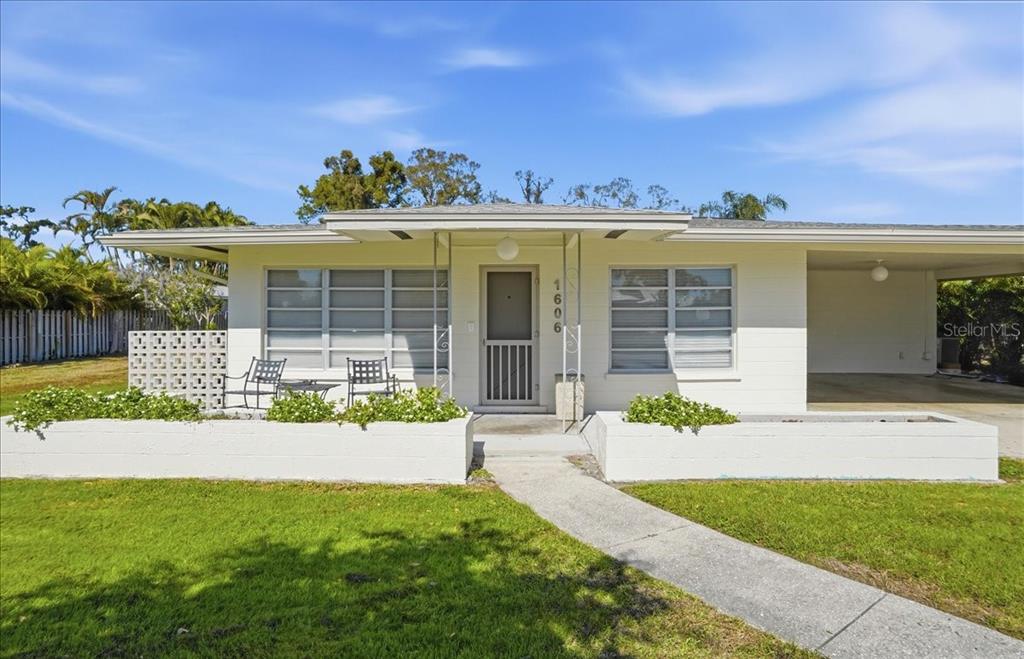A white, single-story house features a flat roof, a carport, and a front patio area — 1606 4TH STREET W, PALMETTO, FL