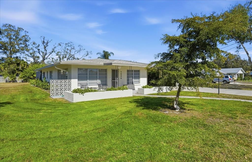 A single-story white house features a decorative breeze block wall and a front patio area — 1606 4TH STREET W, PALMETTO, FL
