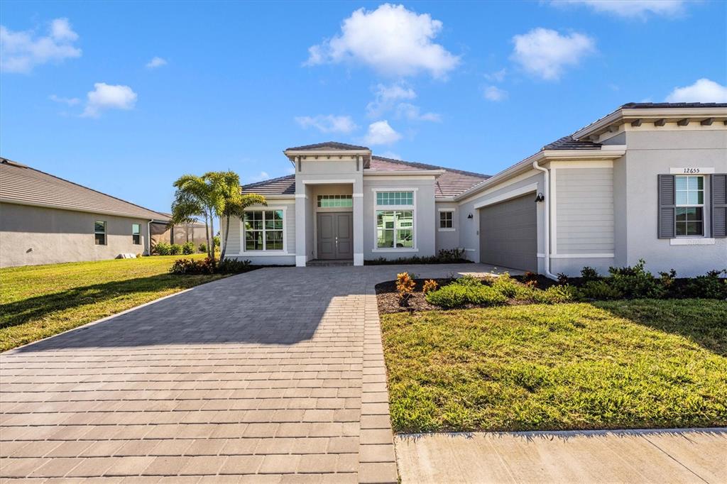 A single-story house with a paved driveway, gray exterior, and a two-car garage — 12655 WELLEN GOLF STREET, VENICE, FL