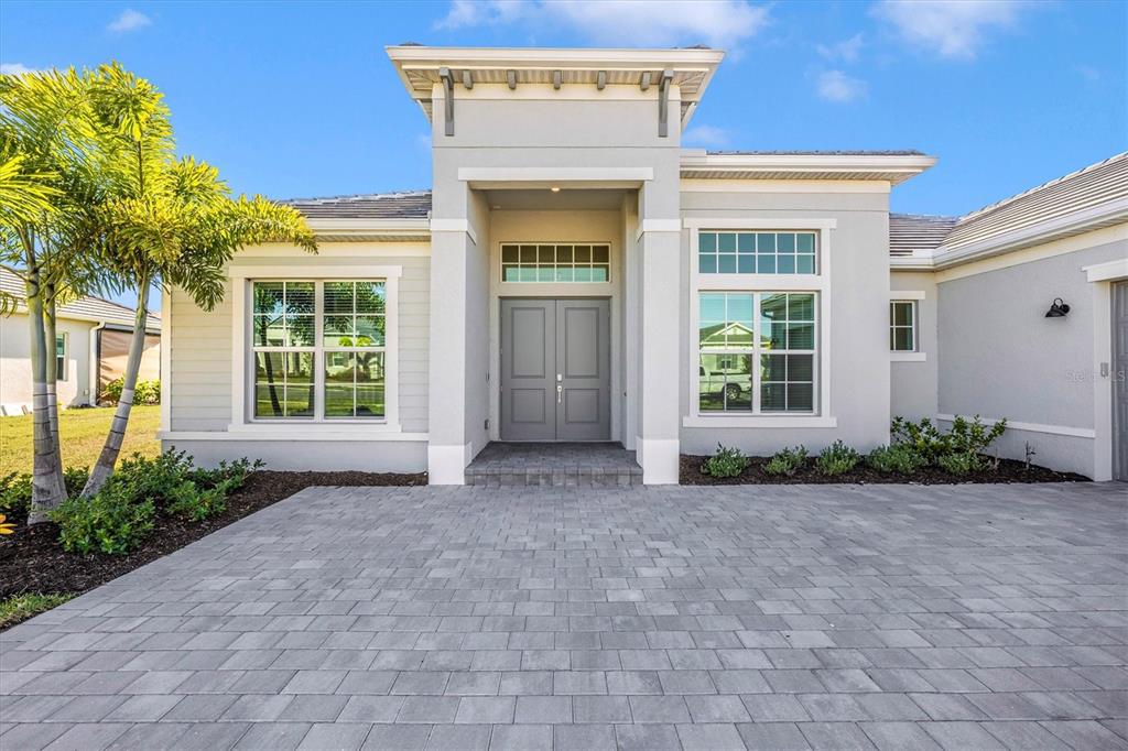 A gray single-story house features a paved driveway, double front doors, and a palm tree — 12655 WELLEN GOLF STREET, VENICE, FL