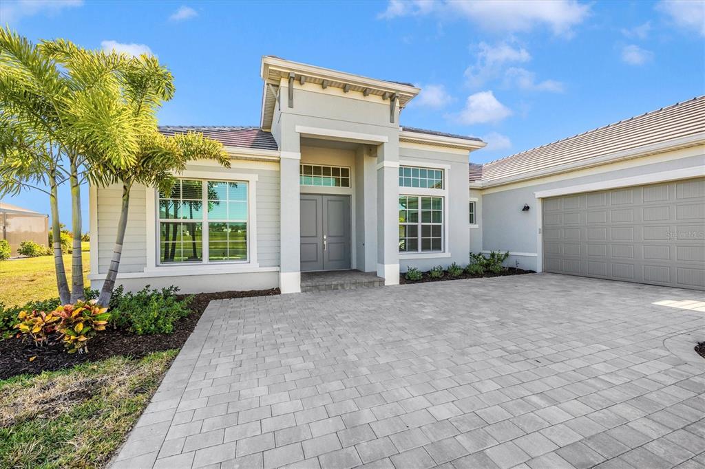A single-story house with a gray exterior, double front doors, and a paved driveway — 12655 WELLEN GOLF STREET, VENICE, FL