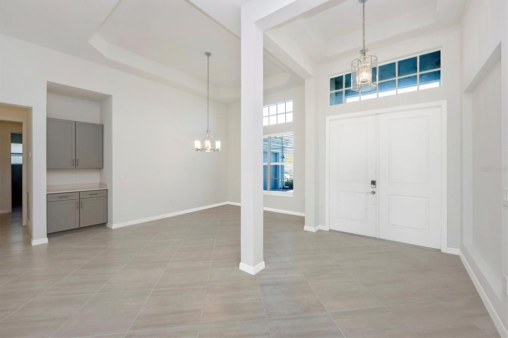 An entryway and dining area with white walls, gray tile flooring, and a double door — 12655 WELLEN GOLF STREET, VENICE, FL