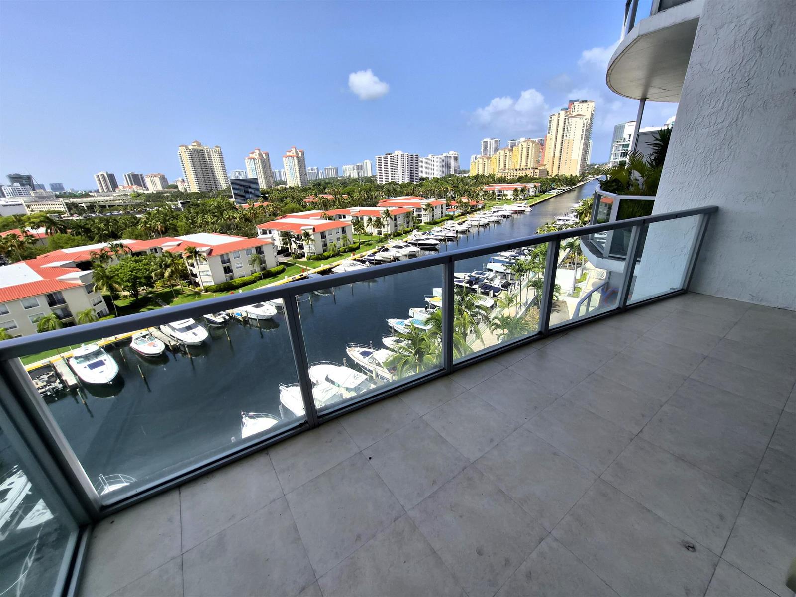 A balcony with a glass railing overlooks a canal filled with boats and city buildings — 3029 NE 188th Street, Aventura FL 33180, AVENTURA, FL