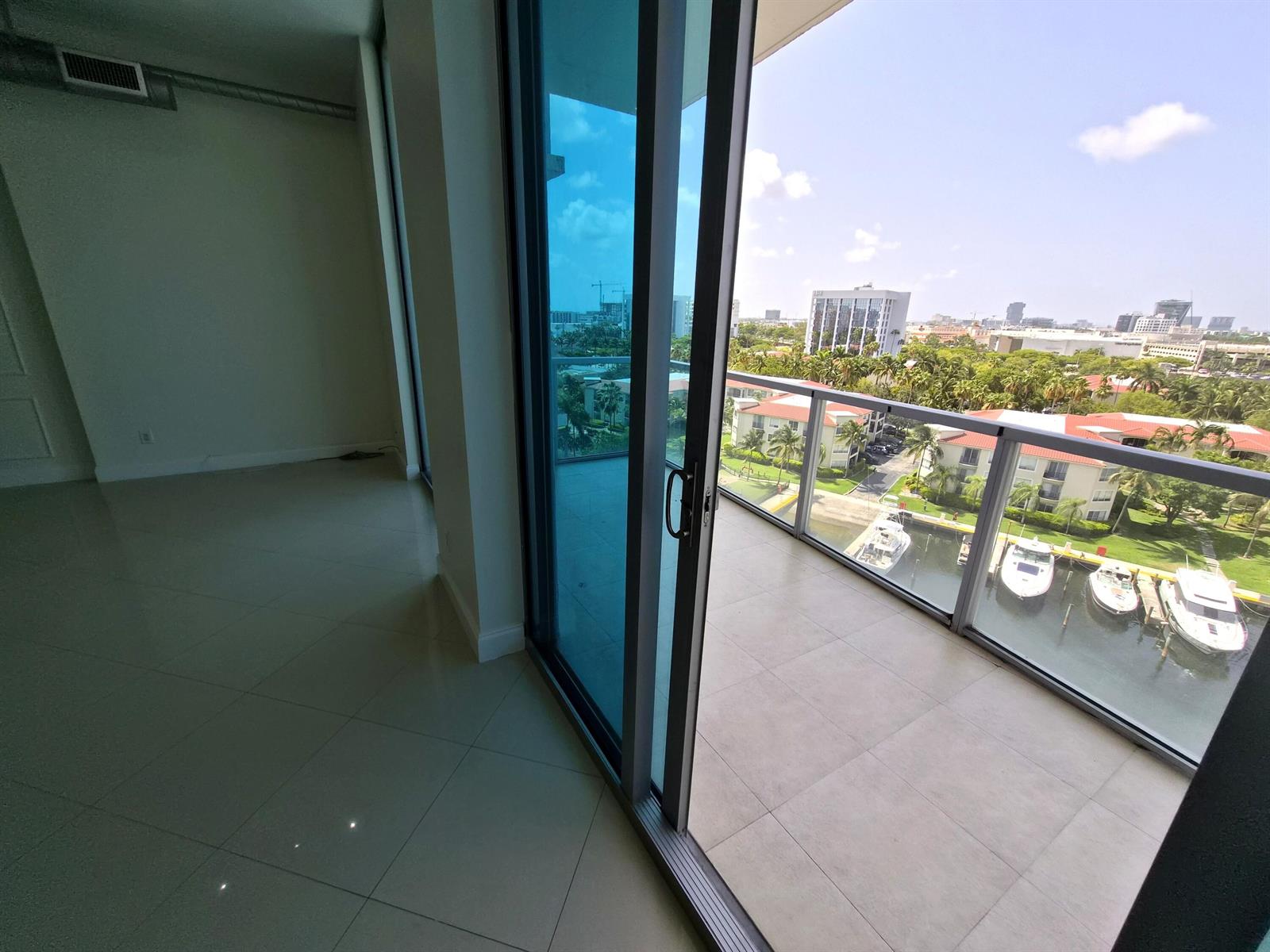 An interior room with tile flooring leads to a balcony overlooking a marina and buildings — 3029 NE 188th Street, Aventura FL 33180, AVENTURA, FL