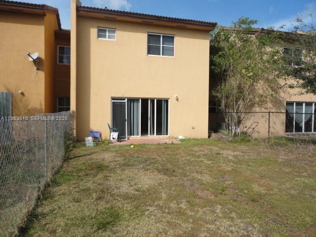 A two-story tan stucco townhouse with a sliding glass door and a fenced backyard — 875 SW 6th Pl, Florida City FL 33034, FLORIDA CITY, FL