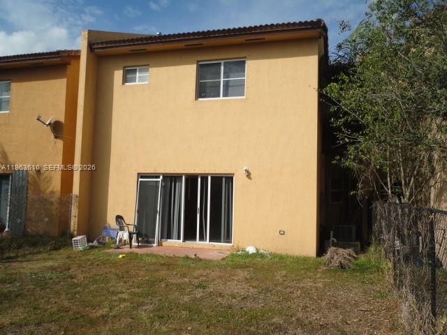 The rear exterior of a two-story tan stucco townhouse features a sliding glass door — 875 SW 6th Pl, Florida City FL 33034, FLORIDA CITY, FL