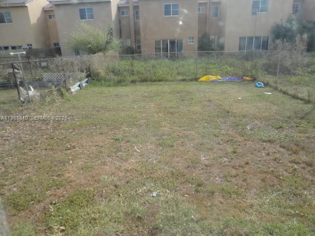 A fenced-in, grassy backyard sits behind a multi-story residential building — 875 SW 6th Pl, Florida City FL 33034, FLORIDA CITY, FL