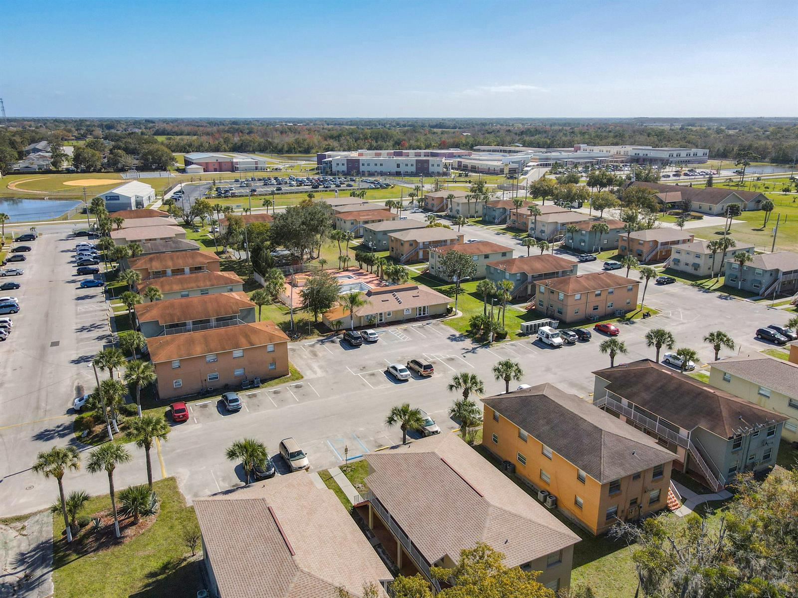 An aerial view shows multiple multi-story apartment buildings surrounded by parking lots and palm trees — 714 Michigan Court # 1, FL 34769, FL