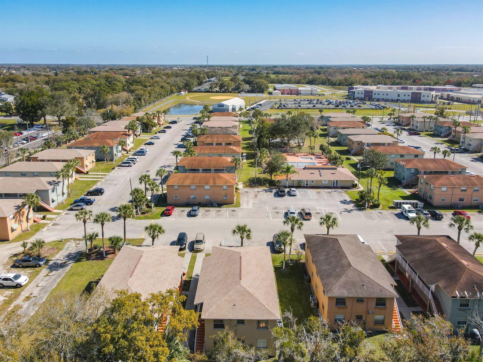 An aerial view of a multi-building apartment complex with parking lots and palm trees — 714 Michigan Court # 1, FL 34769, FL