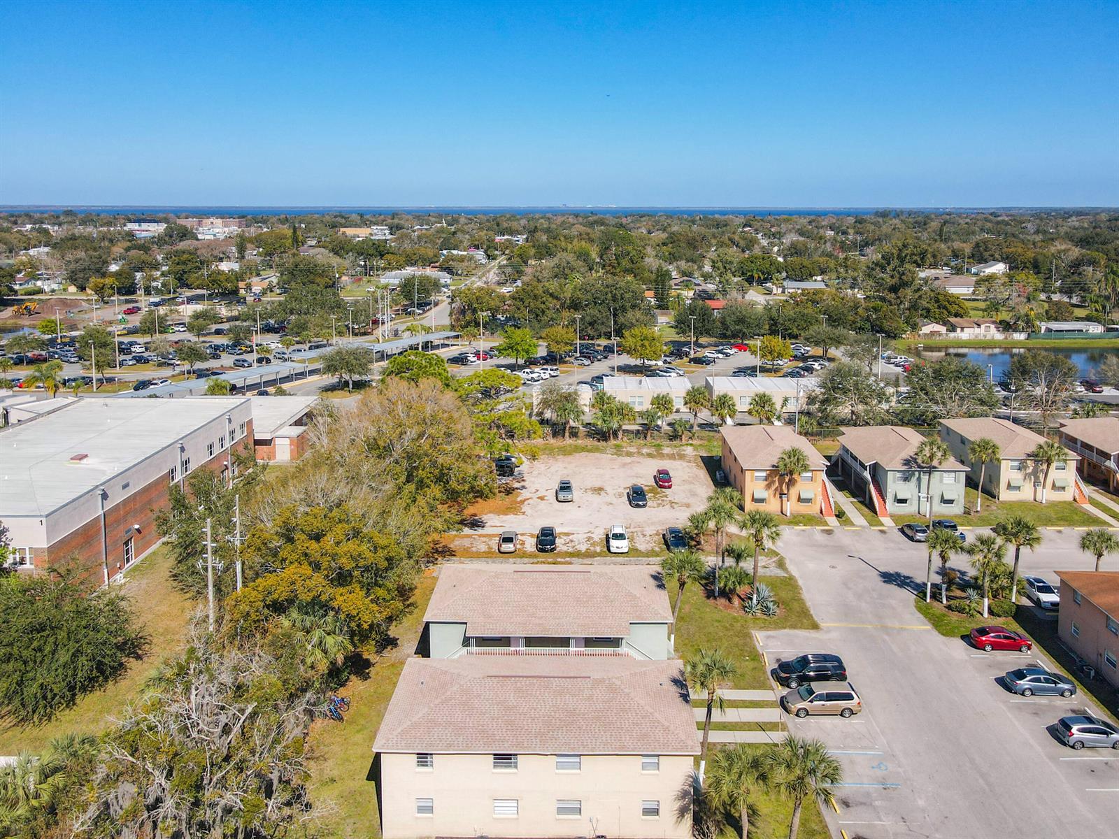 An aerial view shows apartment buildings, a parking lot, and surrounding trees under a clear sky — 714 Michigan Court # 1, FL 34769, FL