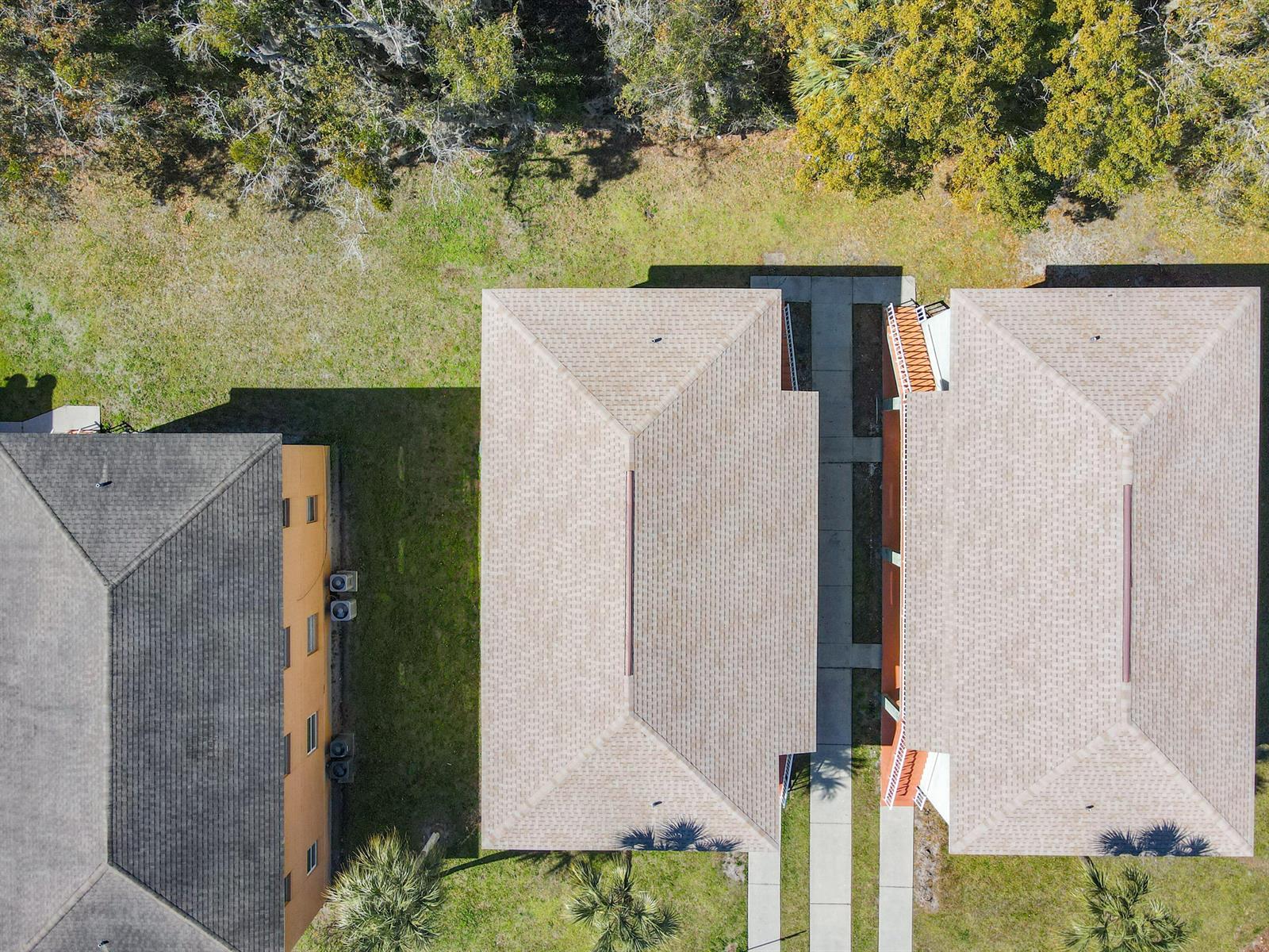 An aerial view shows three residential buildings with shingled roofs surrounded by grass and trees — 714 Michigan Court # 1, FL 34769, FL