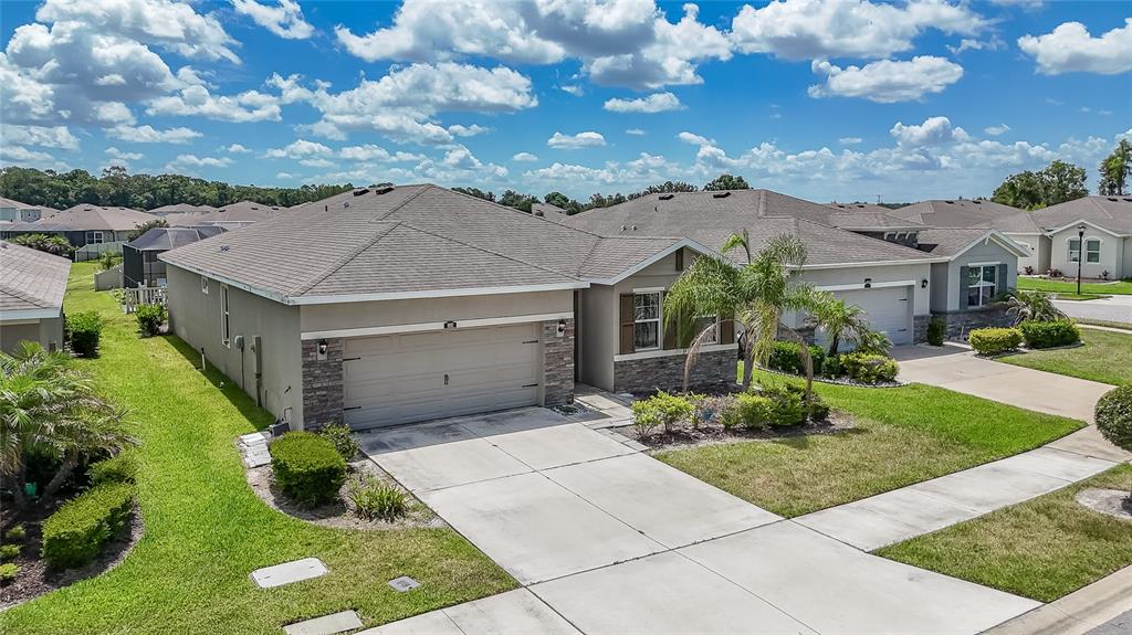 An aerial view of a suburban house with a two-car garage and a landscaped lawn — 1092 PIPESTONE PLACE, WESLEY CHAPEL, FL