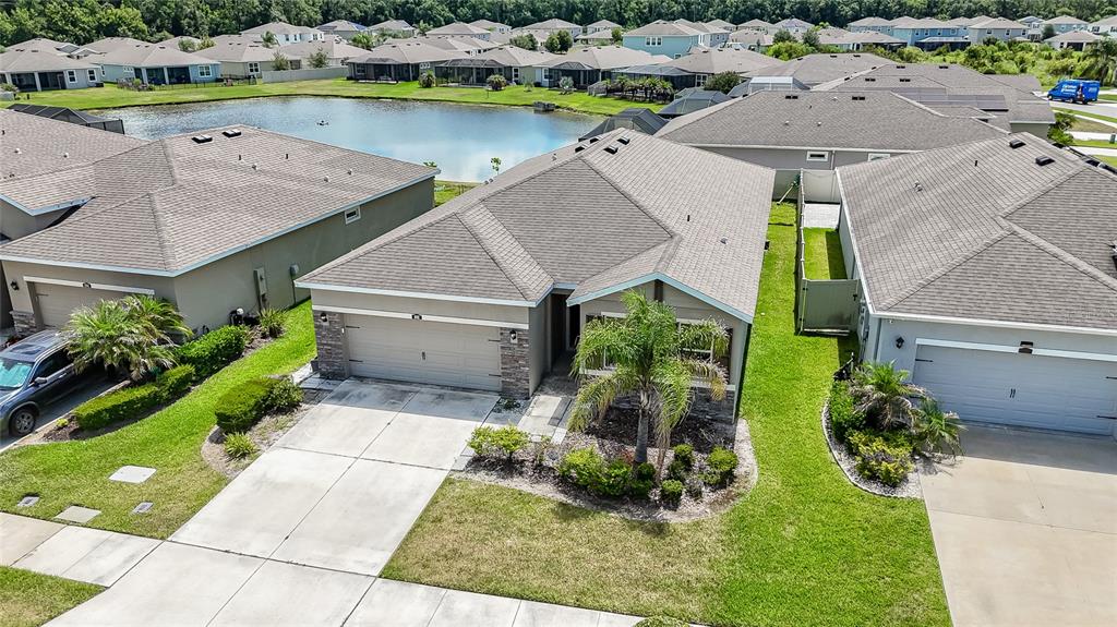 An aerial view shows a suburban house with a concrete driveway and a nearby pond — 1092 PIPESTONE PLACE, WESLEY CHAPEL, FL