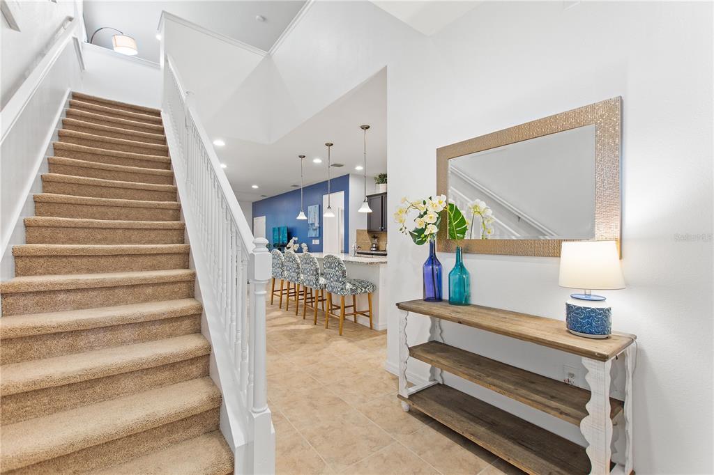 A carpeted staircase leads up beside a foyer featuring a wooden console table and mirror — 1861 NICE CT, KISSIMMEE, FL