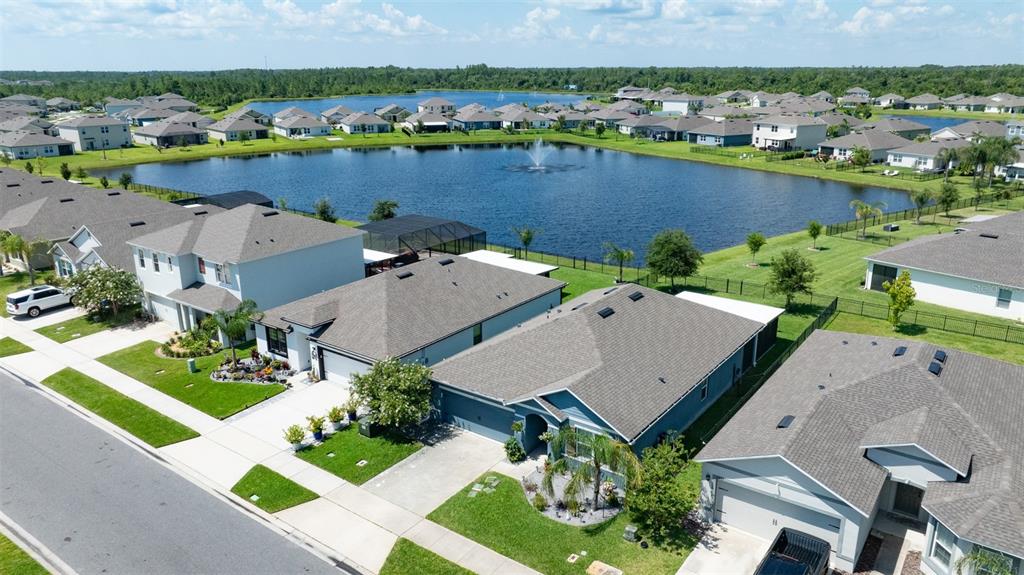 An aerial view shows suburban houses with gray roofs situated around a central retention pond — 2635 NEVERLAND DRIVE, NEW SMYRNA BEACH, FL