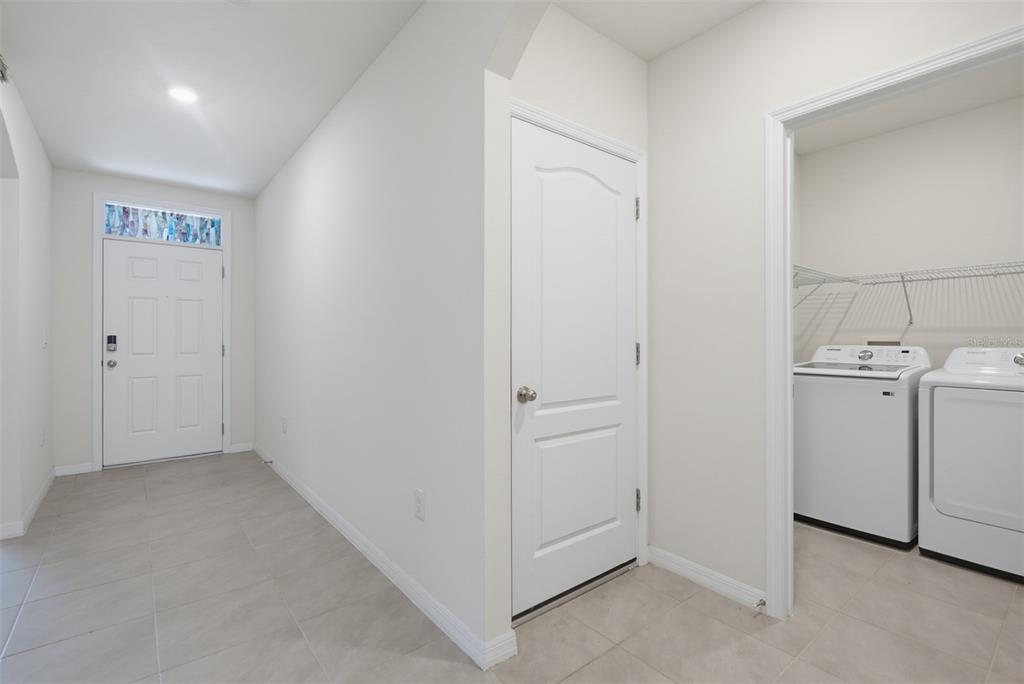 A hallway features a white front door, a closed interior door, and an adjacent laundry room — 2635 NEVERLAND DRIVE, NEW SMYRNA BEACH, FL