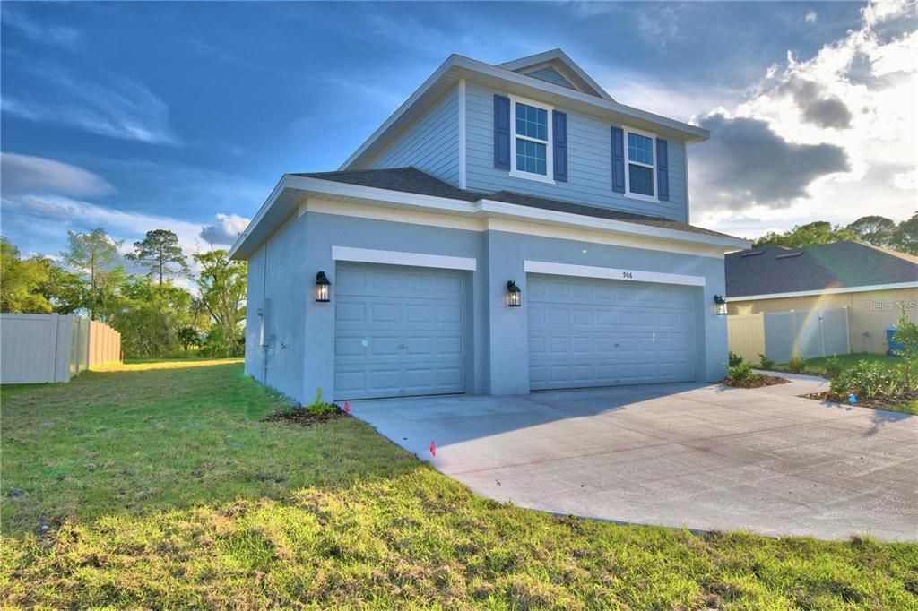 A two-story house with a light blue exterior, a three-car garage, and a concrete driveway — 906 SOFIA LANE, DAVENPORT, FL