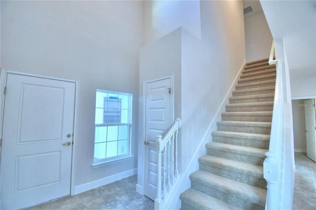 An entryway features a front door, a window, a carpeted staircase, and tile flooring — 906 SOFIA LANE, DAVENPORT, FL