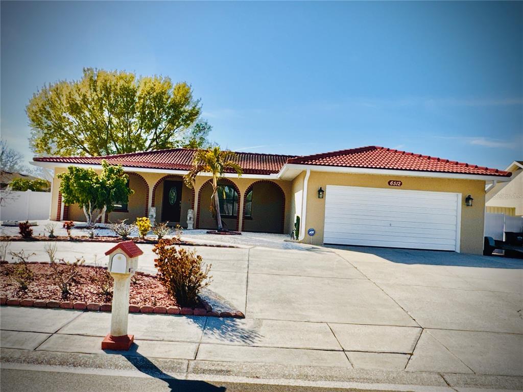 A single-story house with a red tile roof, arched entryway, and a two-car garage — 6512 MANILA PALM WAY, APOLLO BEACH, FL