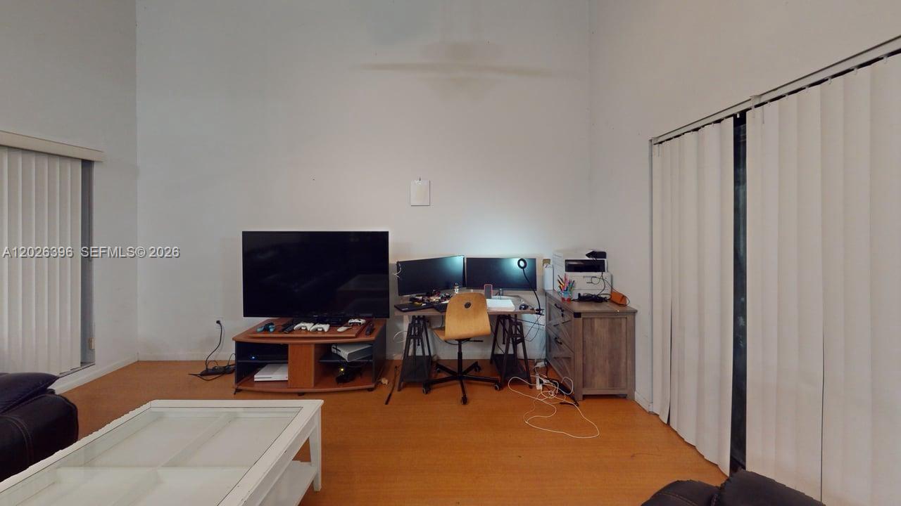 A living room features a television stand, a desk with dual monitors, and wood-look flooring — 15552 SW 54th Ter, Miami FL 33185, MIAMI, FL