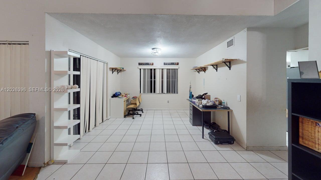 A room with white tile floors, two desks, wall-mounted shelves, and a sliding glass door — 15552 SW 54th Ter, Miami FL 33185, MIAMI, FL