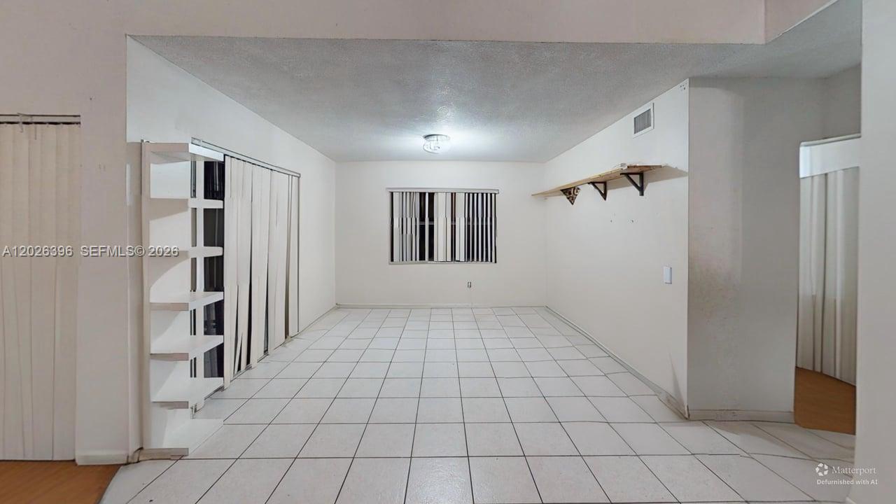 An empty room features white tiled floors, white walls, a window, and wall-mounted shelving — 15552 SW 54th Ter, Miami FL 33185, MIAMI, FL