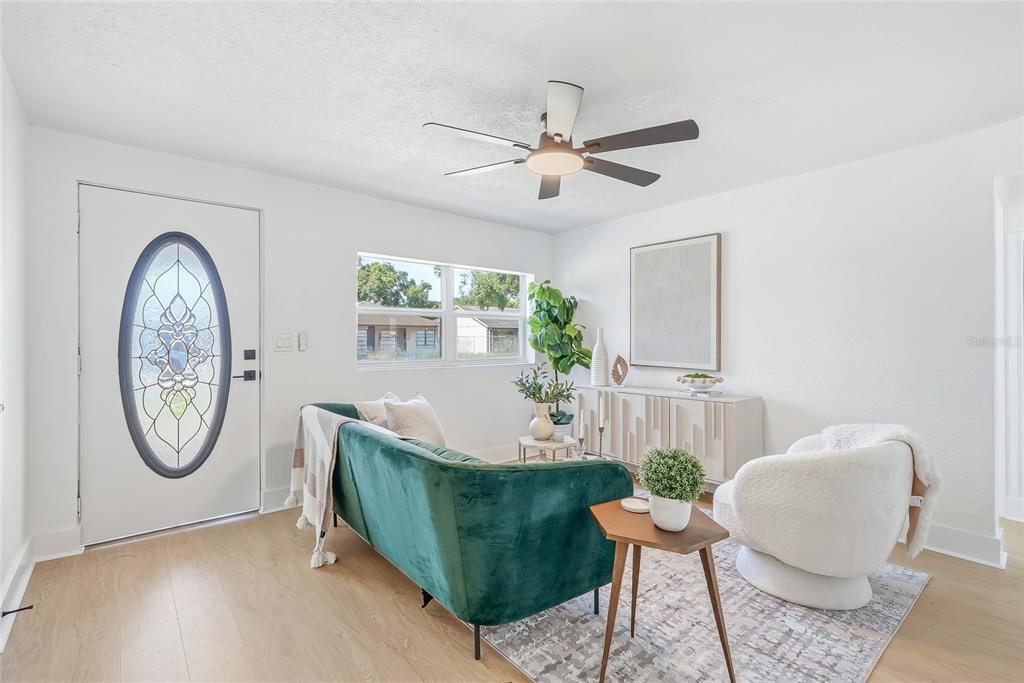A living room features a green velvet sofa, a ceiling fan, and a front door — 2110 E NEDRO ROAD, TAMPA, FL