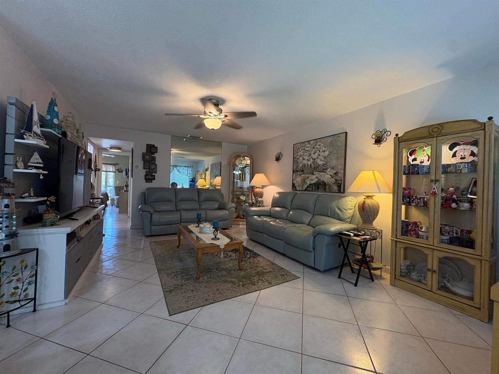 A living room features light tile floors, two leather sofas, a coffee table, and a display cabinet — 175 Bedford # G, West Palm Beach FL 33417, WEST PALM BEACH, FL