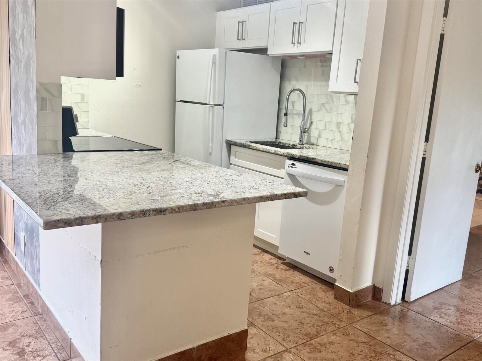 A kitchen features white cabinets, granite countertops, a white refrigerator, and a dishwasher — 21 Crossings Circle # C, Boynton Beach FL 33435, BOYNTON BEACH, FL