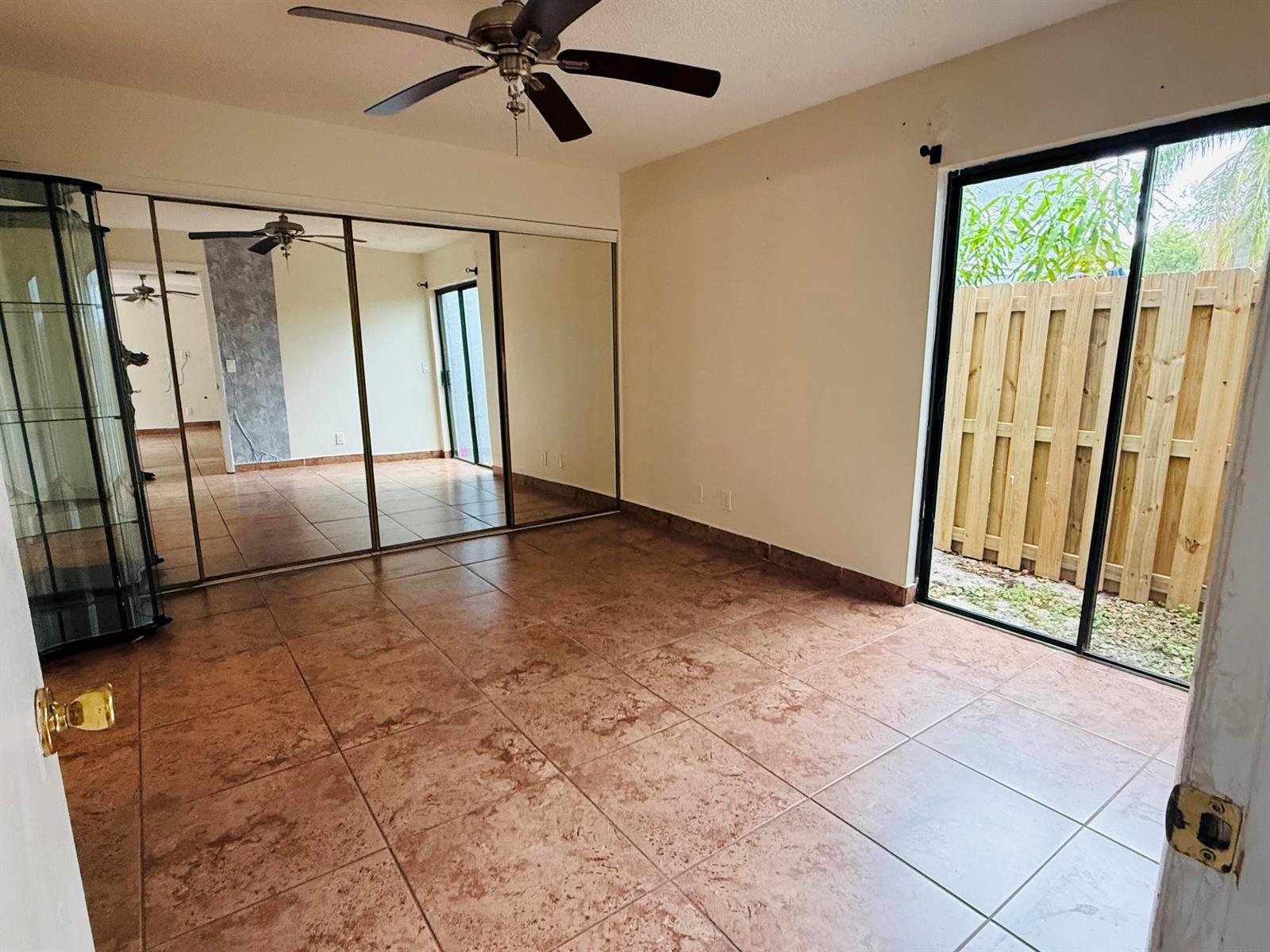 An empty room features large mirrored closet doors, tile flooring, and a sliding glass door — 21 Crossings Circle # C, Boynton Beach FL 33435, BOYNTON BEACH, FL