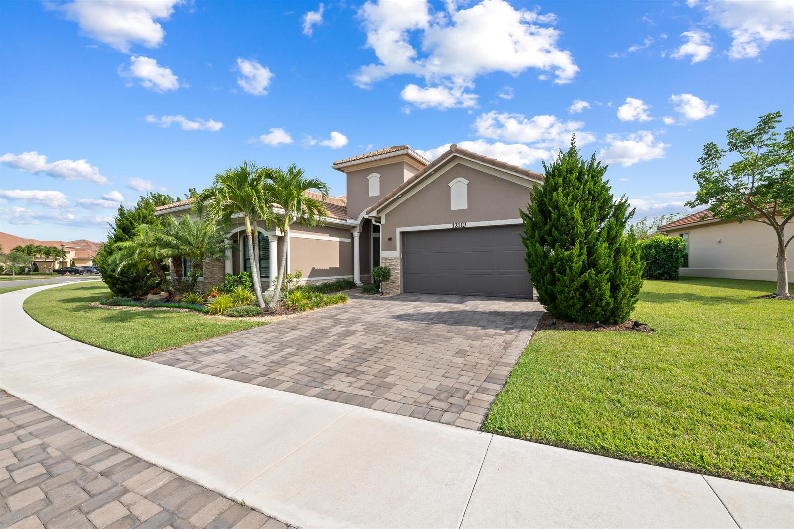 A single-story house with a paved driveway, a two-car garage, and palm trees — 12110 Bastille Circle E, Parkland FL 33076, PARKLAND, FL