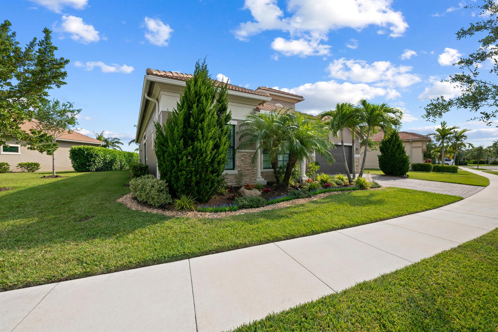 A single-story house with a tiled roof, stone accents, and palm trees in the front yard — 12110 Bastille Circle E, Parkland FL 33076, PARKLAND, FL
