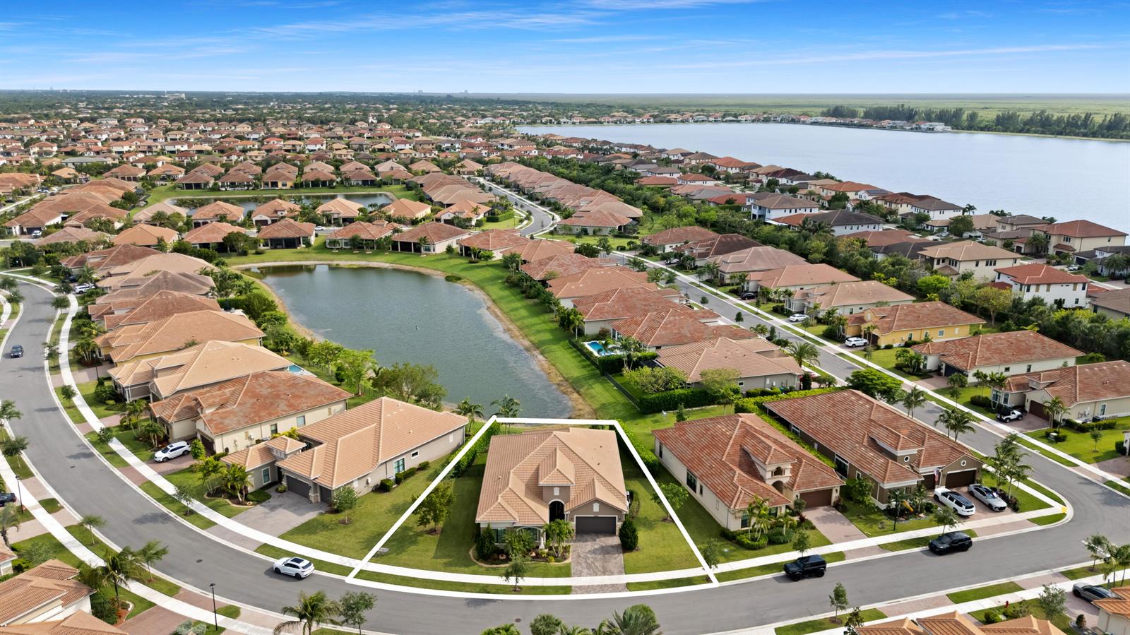 An aerial view shows a suburban neighborhood with a highlighted single-family home near a lake — 12110 Bastille Circle E, Parkland FL 33076, PARKLAND, FL