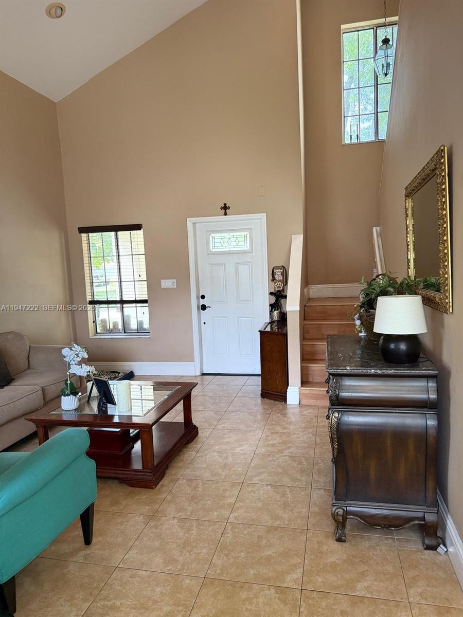 A living room features high ceilings, tile flooring, a staircase, and a front entryway — 14534 SW 144th Ter, Miami FL 33186, MIAMI, FL