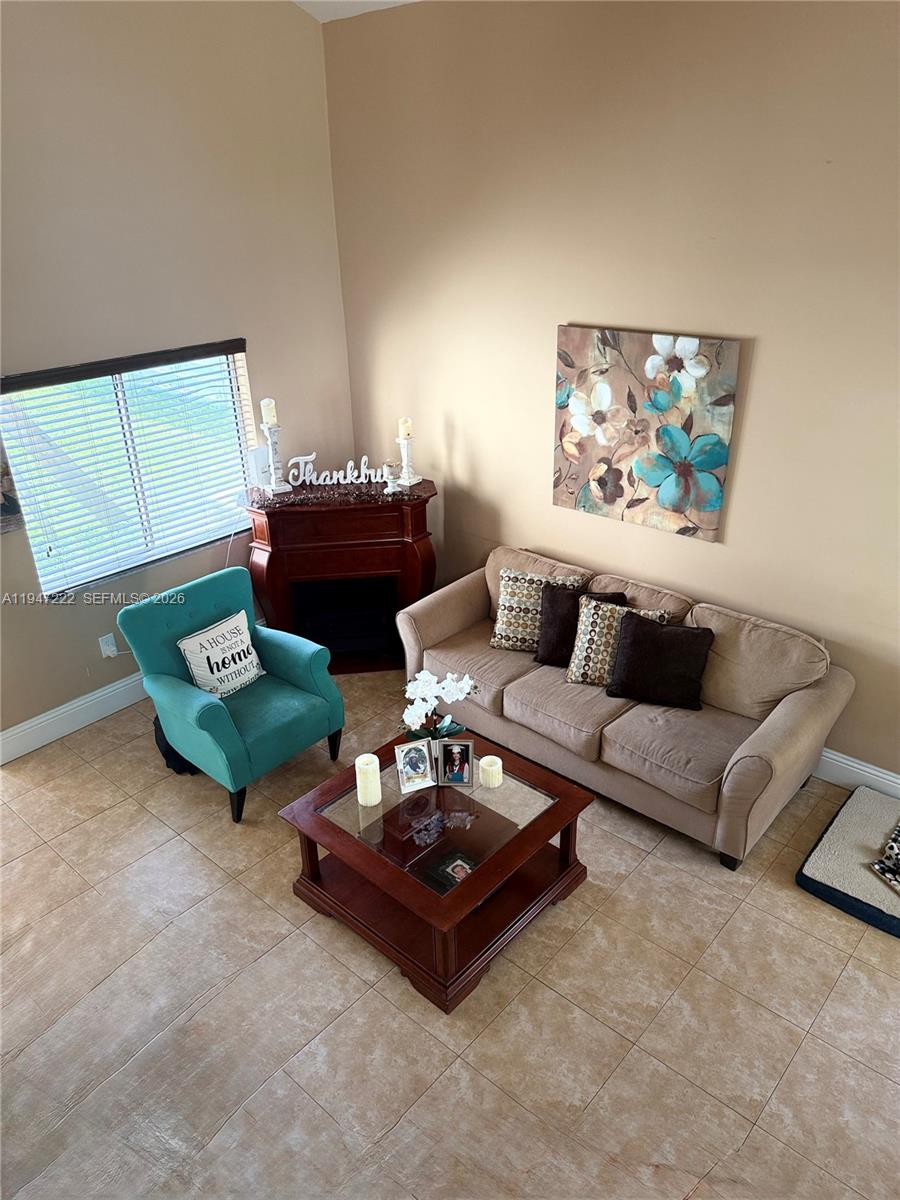 A living room features a beige sofa, a teal armchair, a coffee table, and a fireplace — 14534 SW 144th Ter, Miami FL 33186, MIAMI, FL