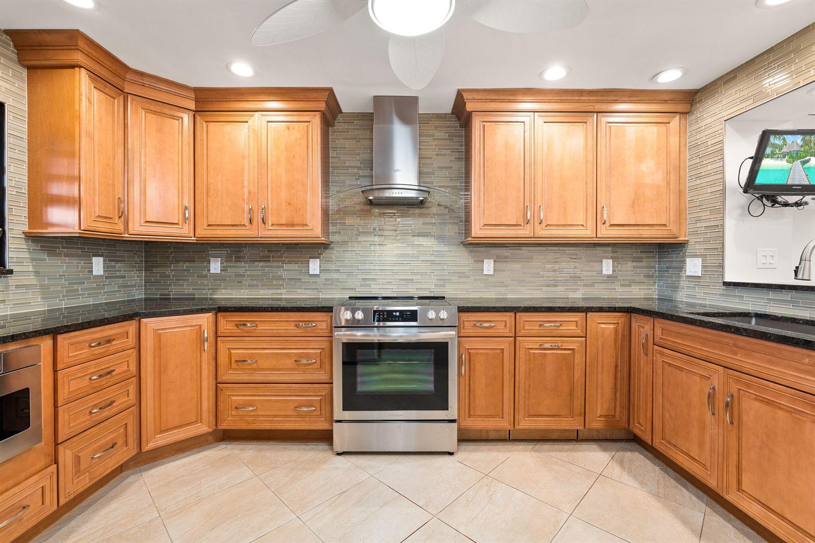 A kitchen features wood cabinets, stainless steel appliances, a tiled backsplash, and dark countertops — 160 SE Saint Lucie Boulevard # 402a, Stuart FL 34996, STUART, FL