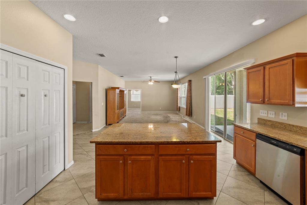A kitchen with a granite-topped island and wood cabinets overlooks an open-concept living area — 6110 39TH COURT E, BRADENTON, FL