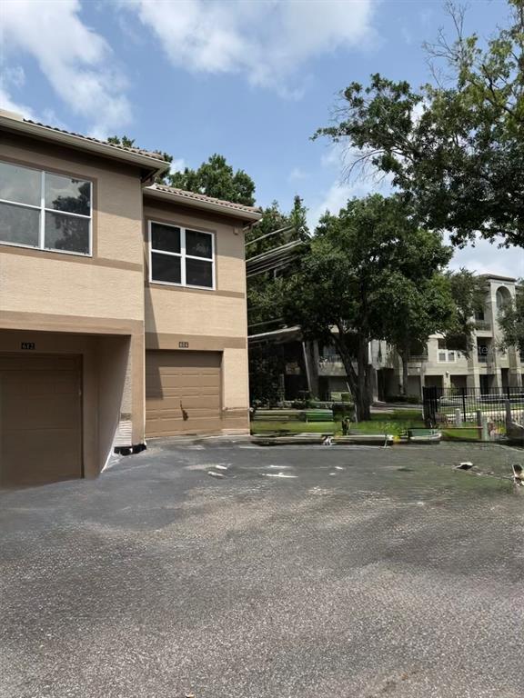 Exterior view of a two-story tan building with attached garages and a paved driveway — 614 ARBOR LAKE LANE UNIT 614, TAMPA, FL