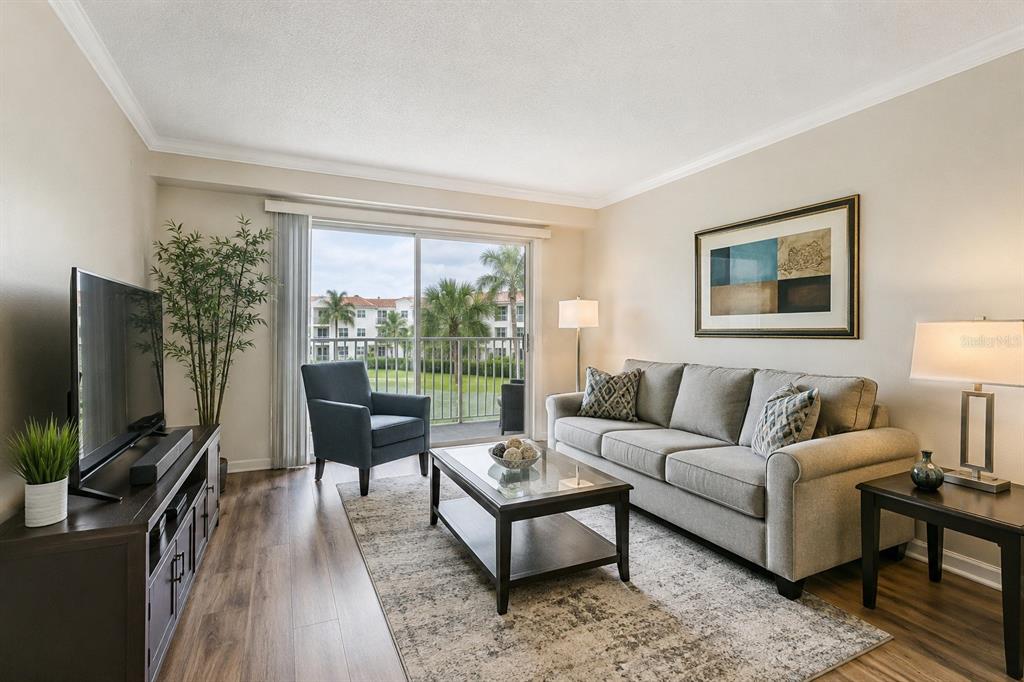 A living room features a grey sofa, dark wood furniture, a rug, and a balcony view — 614 ARBOR LAKE LANE UNIT 614, TAMPA, FL