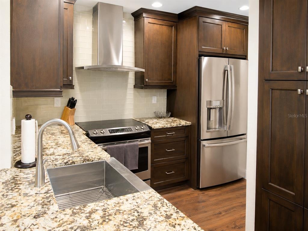A kitchen featuring dark wood cabinets, granite countertops, stainless steel appliances, and a subway tile backsplash — 614 ARBOR LAKE LANE UNIT 614, TAMPA, FL