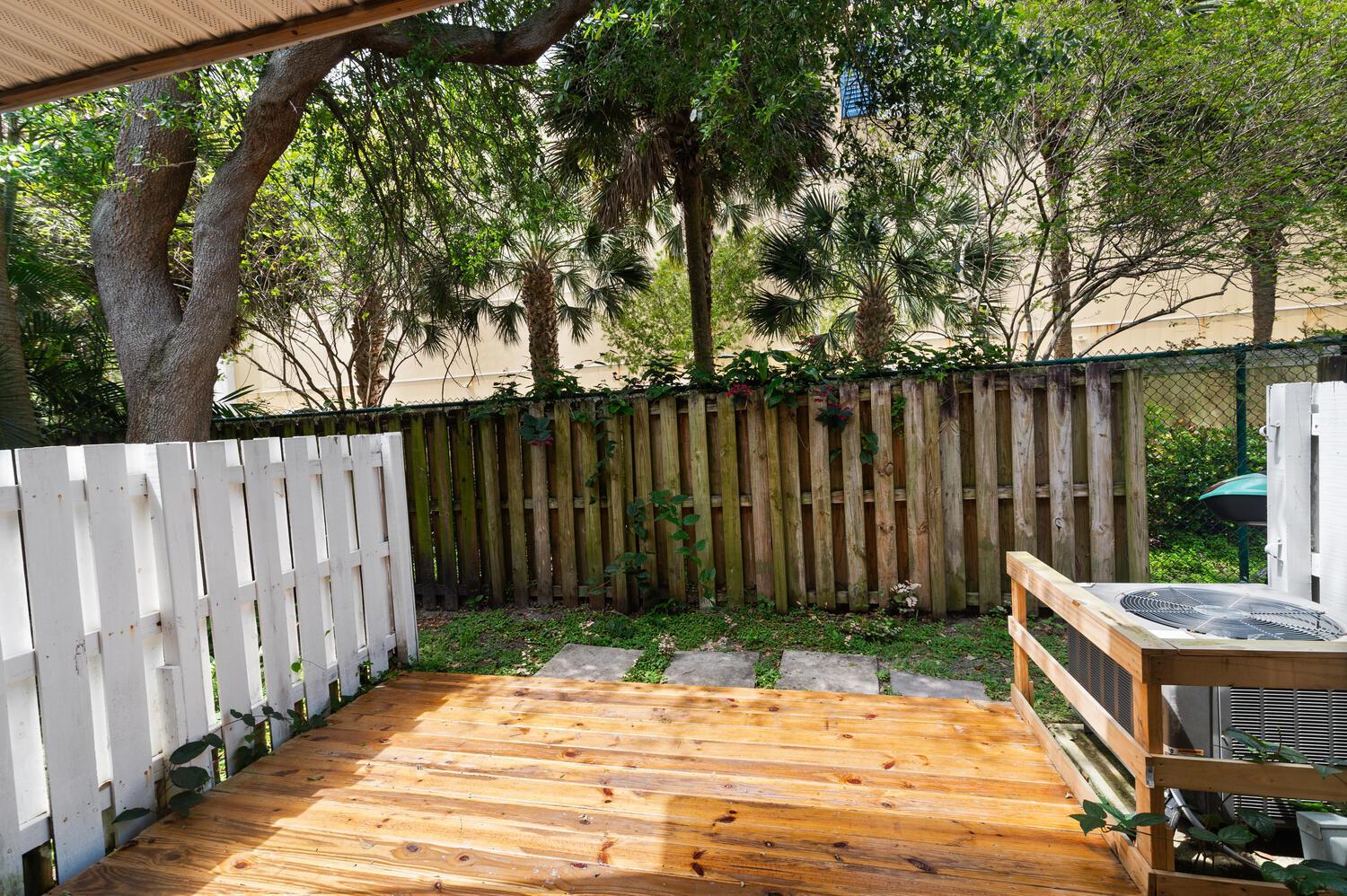A wooden deck sits in a backyard with a white fence and an air conditioning unit — 2521 NE 15th Street, Pompano Beach FL 33062, POMPANO BEACH, FL