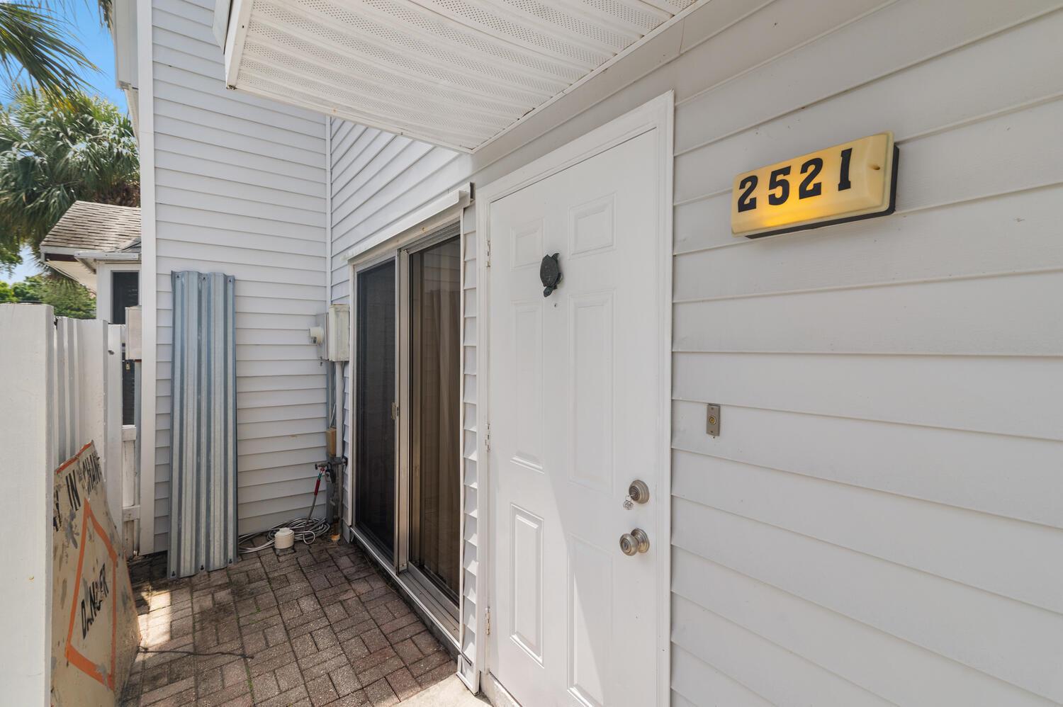 A white front door and sliding glass door are set against light gray horizontal siding — 2521 NE 15th Street, Pompano Beach FL 33062, POMPANO BEACH, FL