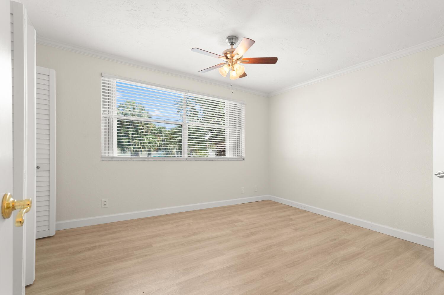 An empty bedroom features light wood-look flooring, white walls, a ceiling fan, and a window — 2521 NE 15th Street, Pompano Beach FL 33062, POMPANO BEACH, FL