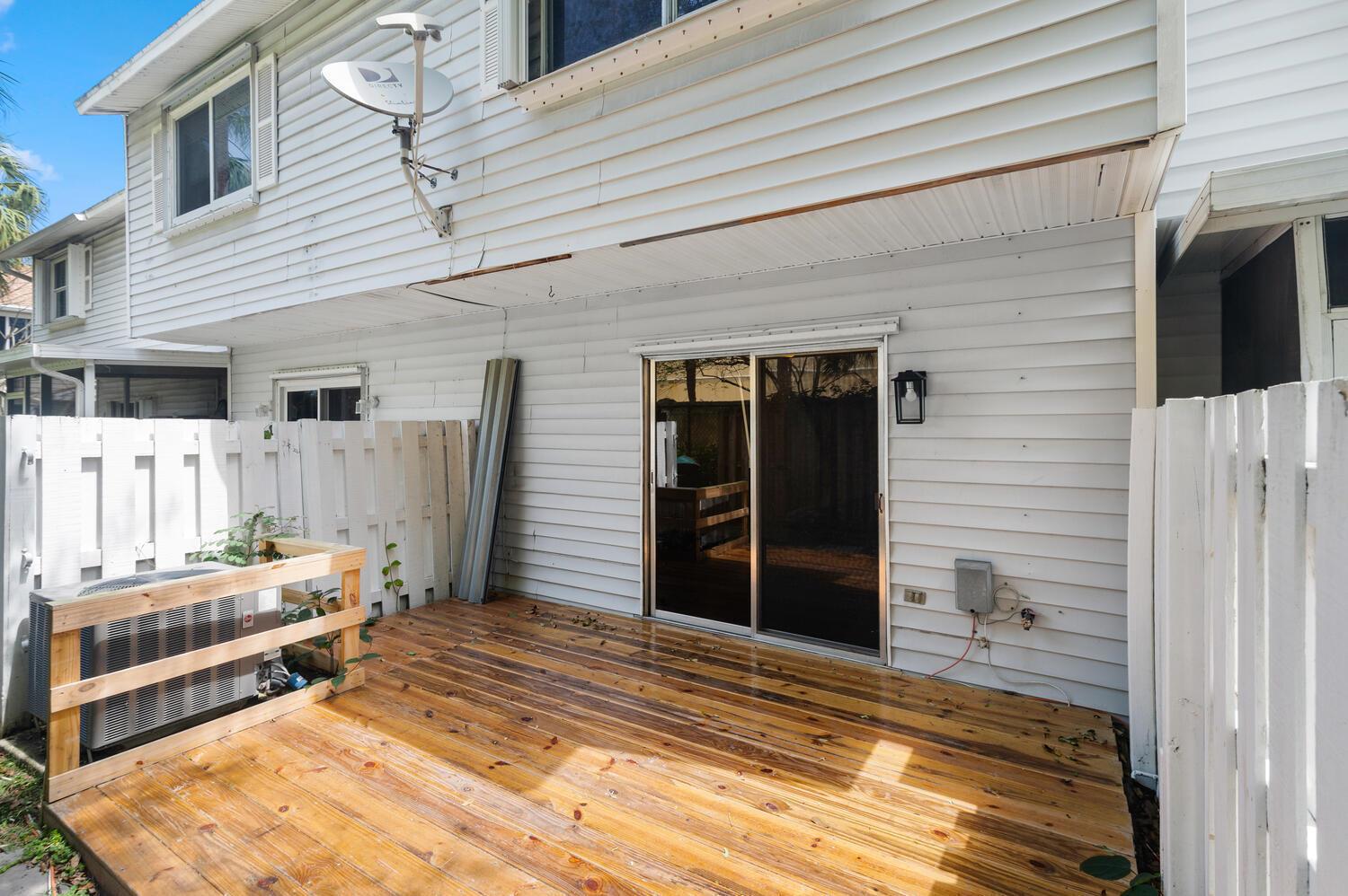 A wooden deck sits outside a white-sided house with a sliding glass door — 2521 NE 15th Street, Pompano Beach FL 33062, POMPANO BEACH, FL