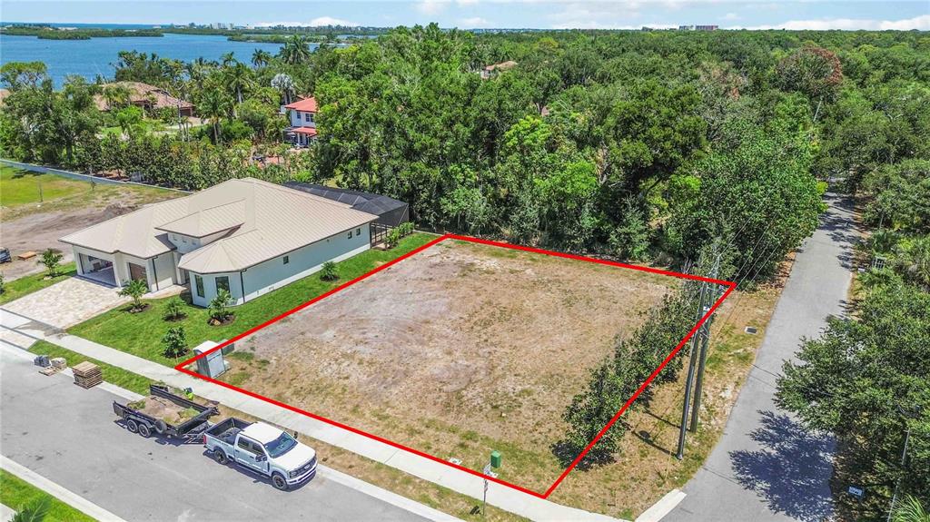 An aerial view shows a vacant, rectangular residential lot outlined in red next to a house — 3820 PARROT BAY COURT, OSPREY, FL