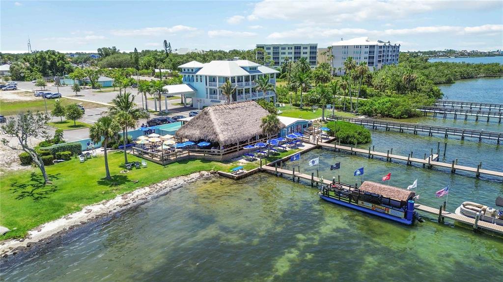 An aerial view shows a waterfront tiki bar and restaurant with a boat dock — 3820 PARROT BAY COURT, OSPREY, FL