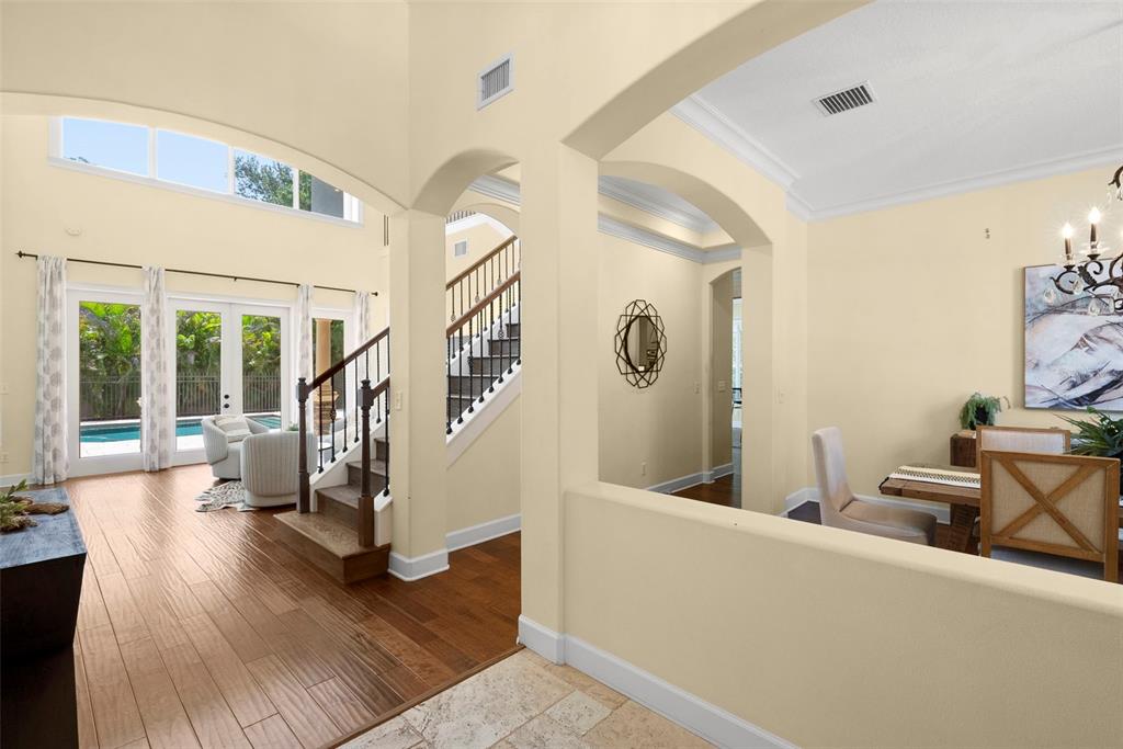 A foyer with tile flooring leads to a living area with hardwood floors and stairs — 2689 WATERS EDGE COURT, DUNEDIN, FL
