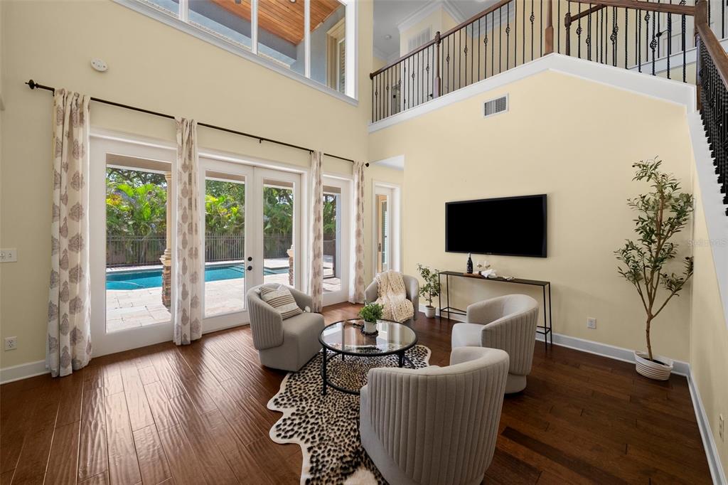 A living room with hardwood floors, three armchairs, a television, and views of a pool — 2689 WATERS EDGE COURT, DUNEDIN, FL