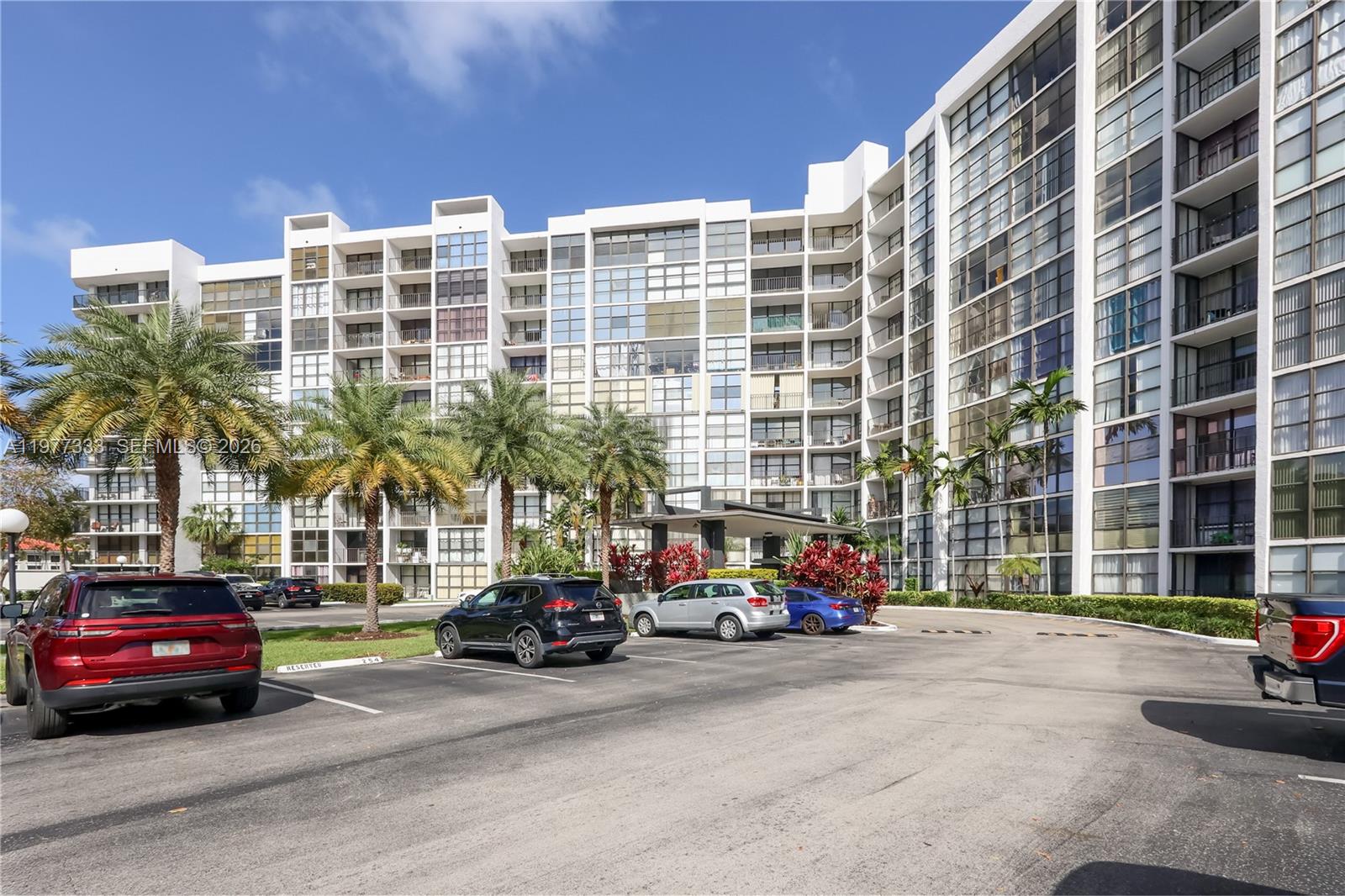 A multi-story residential building with a parking lot and palm trees in front — 1000 Parkview Dr # 222, Hallandale Beach FL 33009, HALLANDALE BEACH, FL